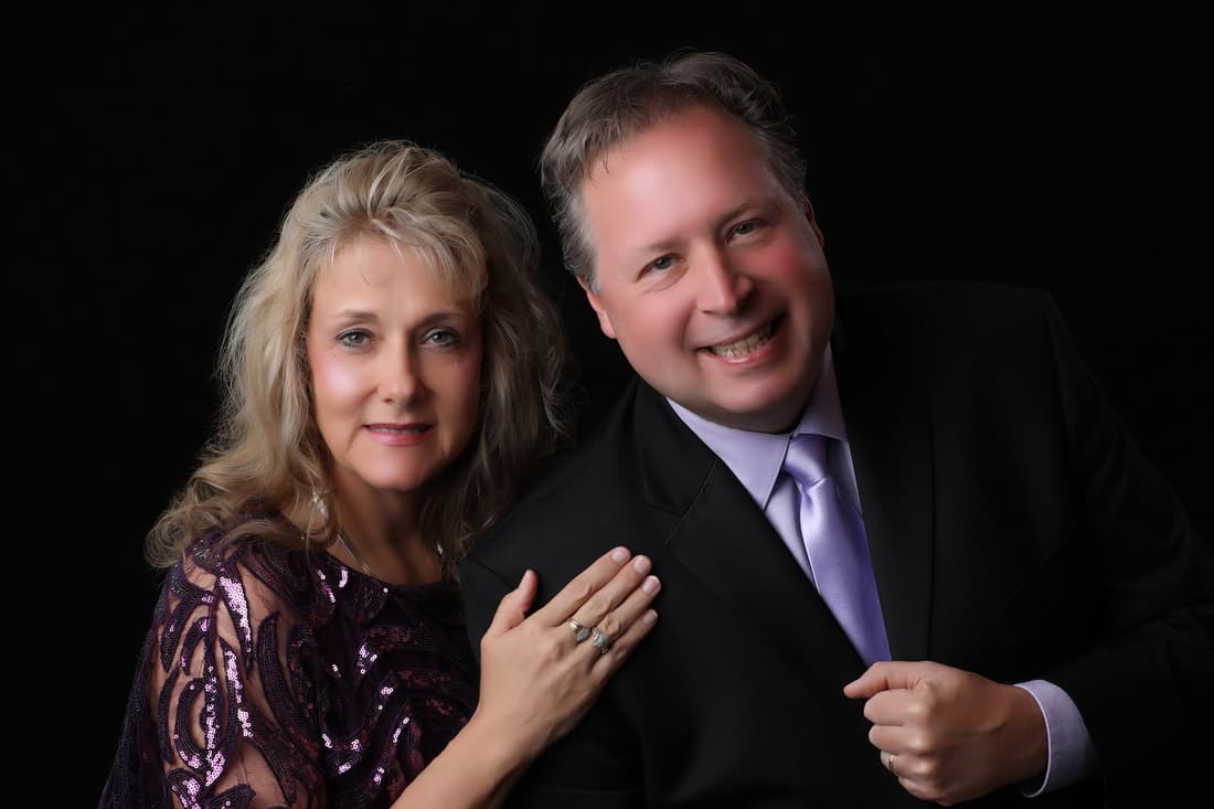 Pastors Joel and Beth Benson standing together, photographed in a studio.