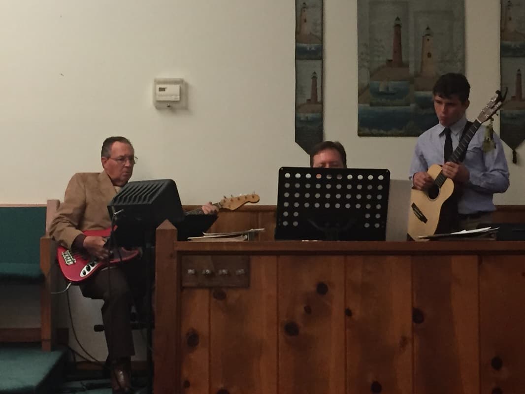 Members of the LOTC praise band playing guitar and keyboard during a service.
